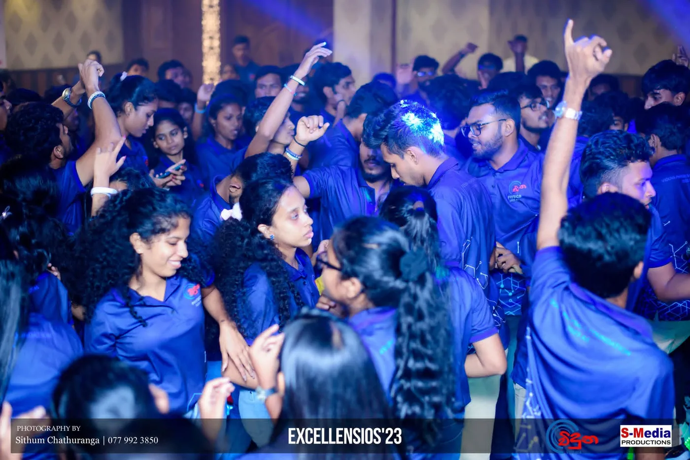 ඝන සිසු සමූහයක් දෑත් ඔසවා, රාත්‍රී උත්සවයේ