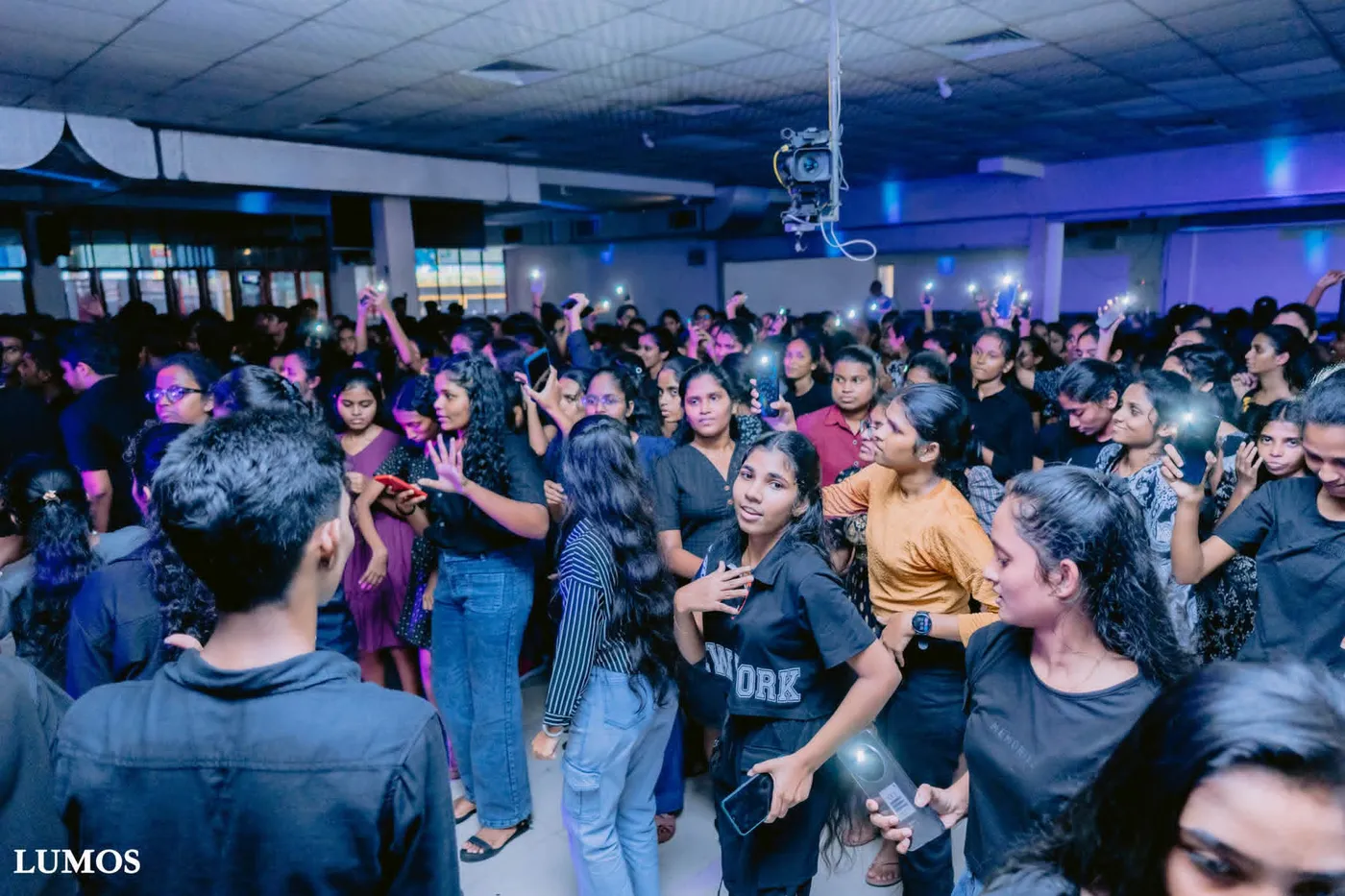 රාත්‍රී උත්සවයේ සිසුන් සමූහයක්, දුරකථන ආලෝකය ඔසවා