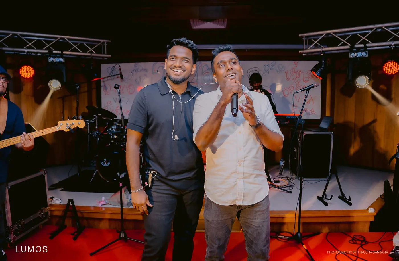 වේදිකාවේ දෙදෙනෙක් එකට මයික්‍රොෆෝනයක් අසල ගී ගයමින්